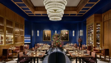 The dining room at Stags Head Steakhouse, Pan Pacific Singapore, featuring deep blue walls, crystal chandelier, and elegantly appointed tables.