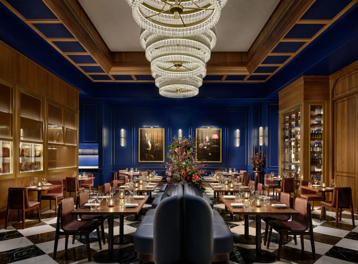 The dining room at Stags Head Steakhouse, Pan Pacific Singapore, featuring deep blue walls, crystal chandelier, and elegantly appointed tables.