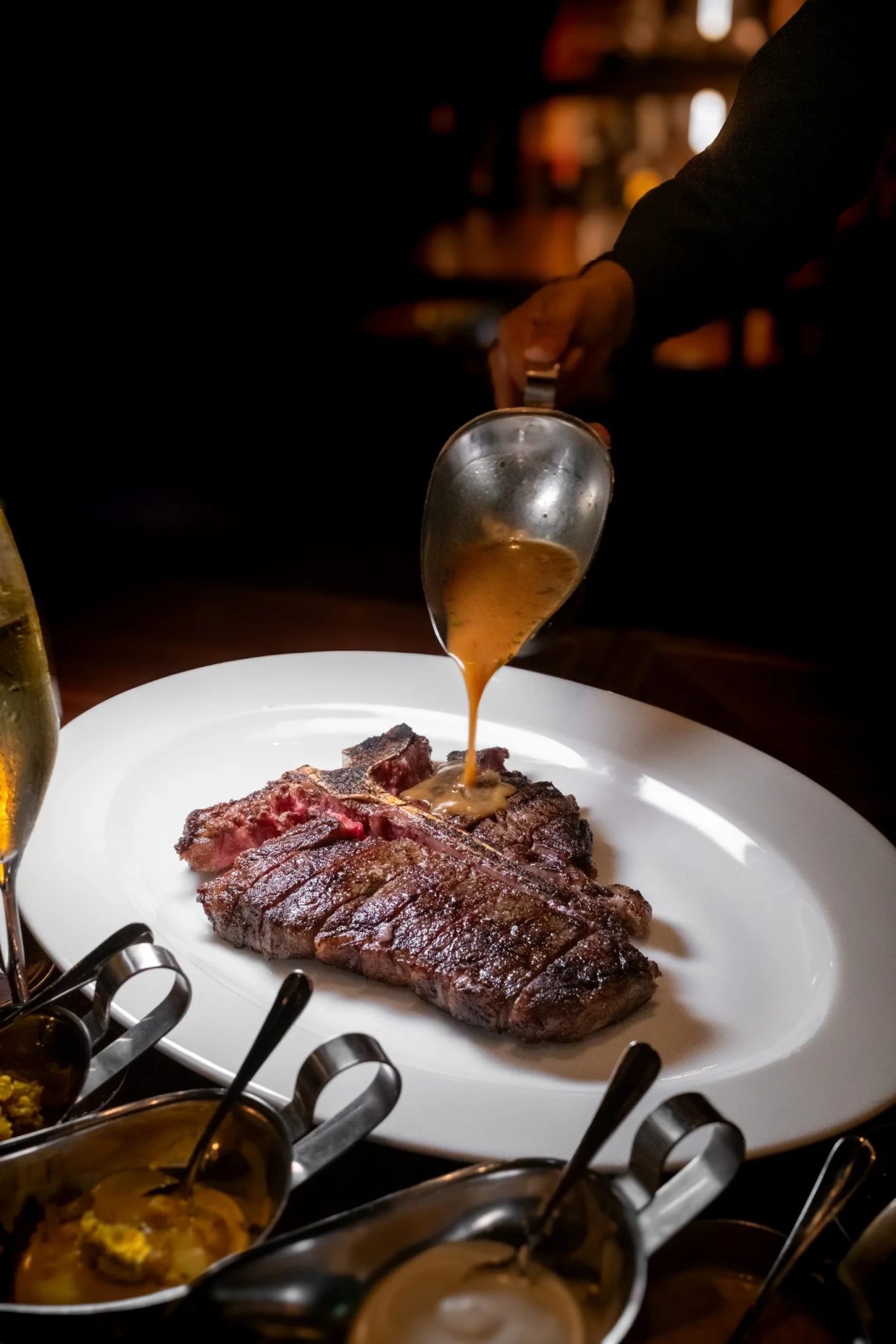 Brown sauce being poured over a medium-rare steak at Stags Head Steakhouse in Pan Pacific Singapore