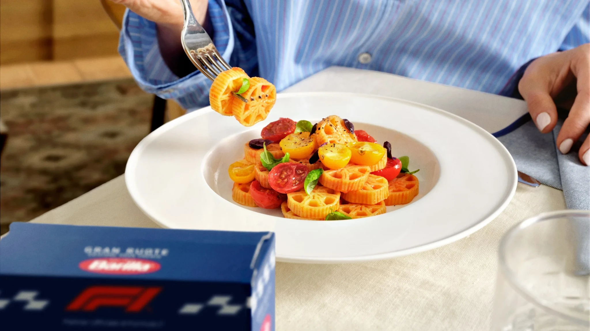 A fork lifts a bite of layered orange and red pasta with vegetables