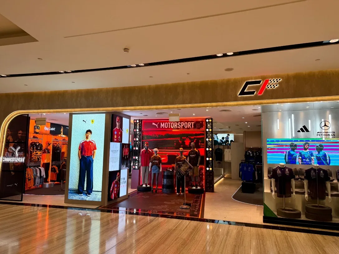 A modern apparel retail storefront with motorsport branding at Jewel Changi Airport, displaying clothing and merchandise on mannequins