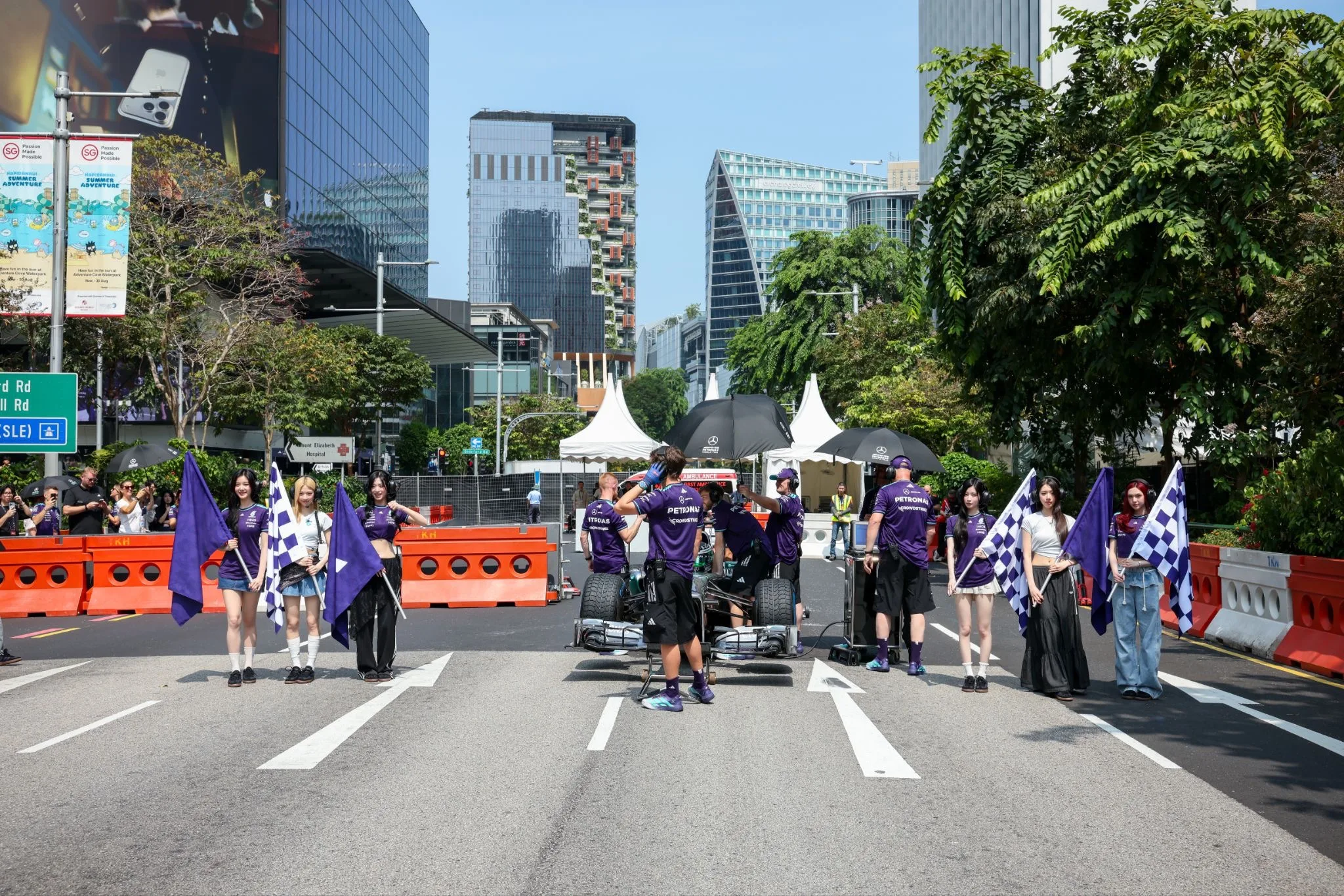 Mercedes-AMG PETRONAS F1 Team race car on Orchard Road with fans holding chequered flags