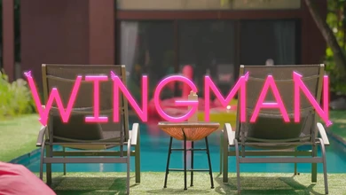 The glowing WINGMAN neon sign behind two lounge chairs at the villa