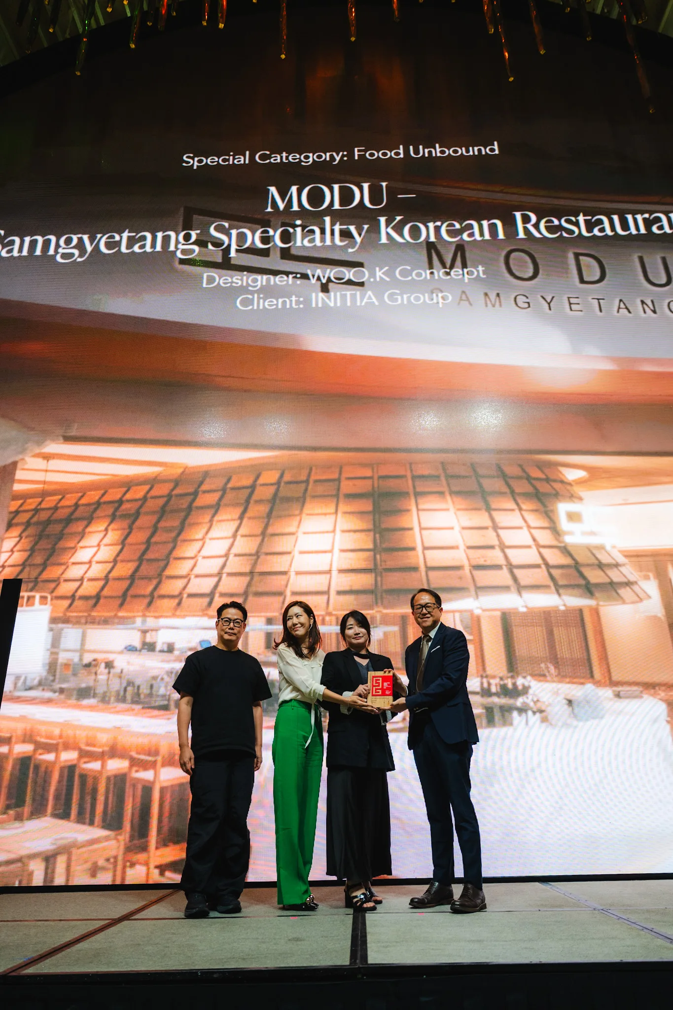 Four people stand before a screen showing MODU, a Korean restaurant designed by WOO.K Concept