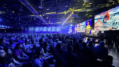 A large crowd watching fighting game matches on giant screens at an Evo event