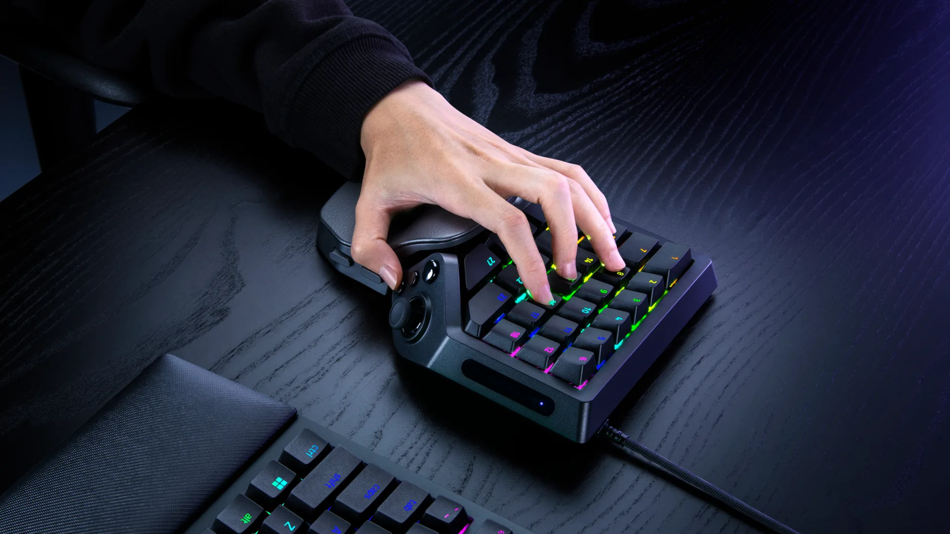 A player's hand resting on the illuminated Razer Tartarus V2 Pro keypad