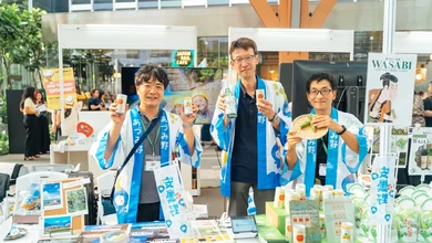 Staff at the Azumino City booth with regional beverages and wasabi products on the counter