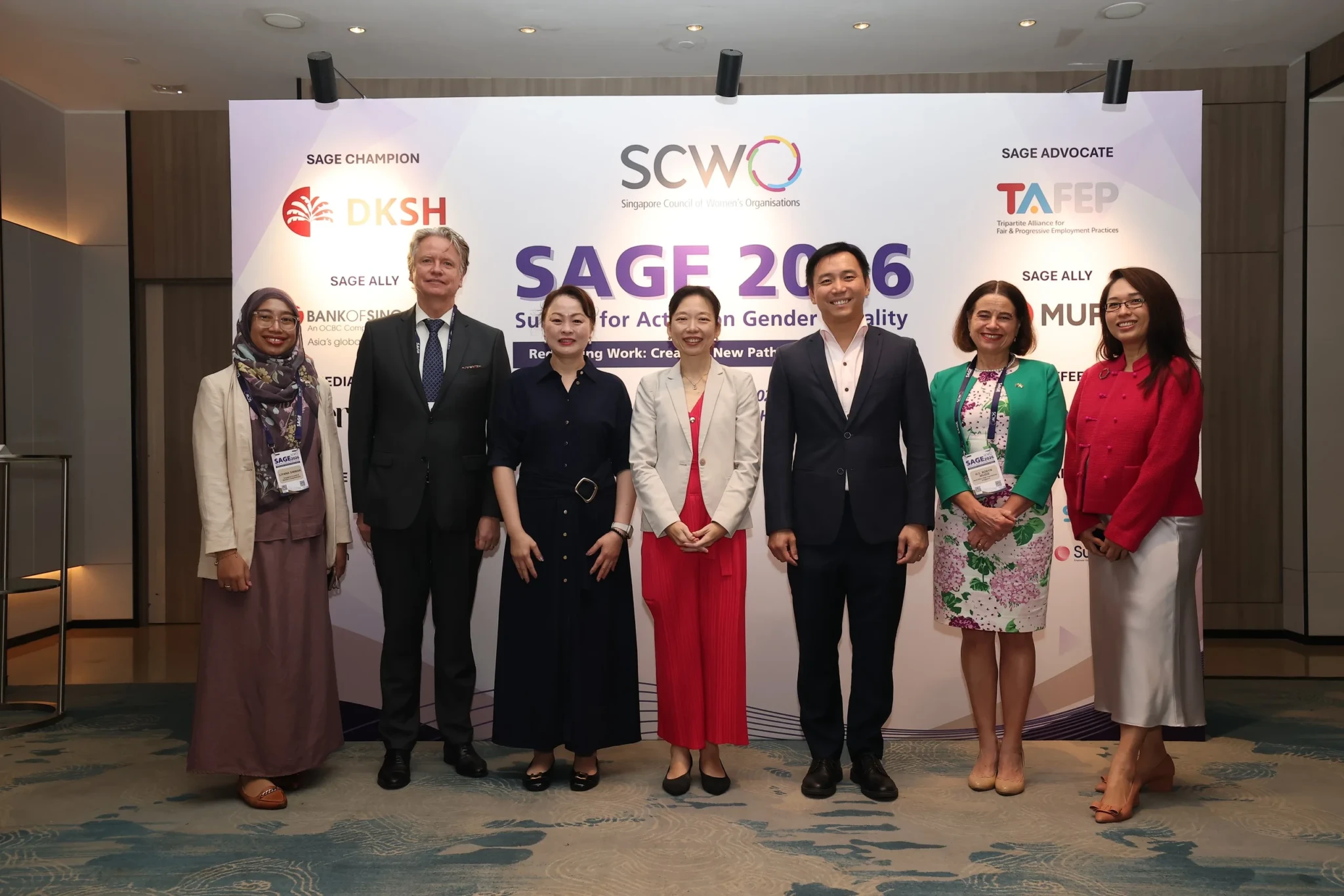 Seven professionals in business attire standing in front of SAGE 2026 event backdrop with organization logos