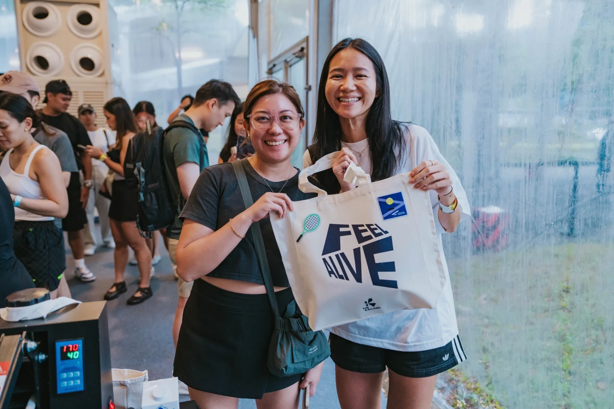 Visitors at the Feel Alive Zone display the official Singapore Tennis Open tote bag