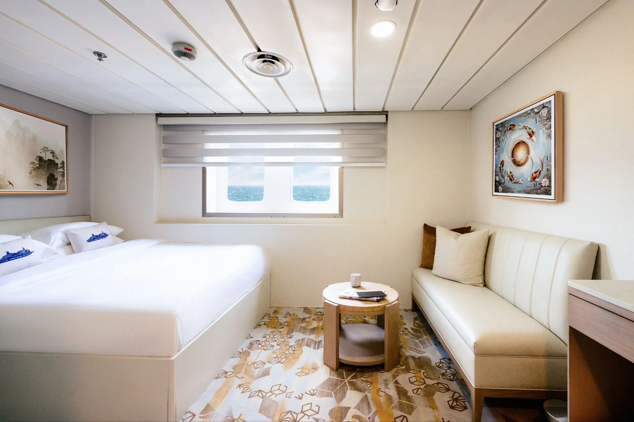 An upgraded cabin aboard World Legacy with a porthole ocean view and modern furnishings