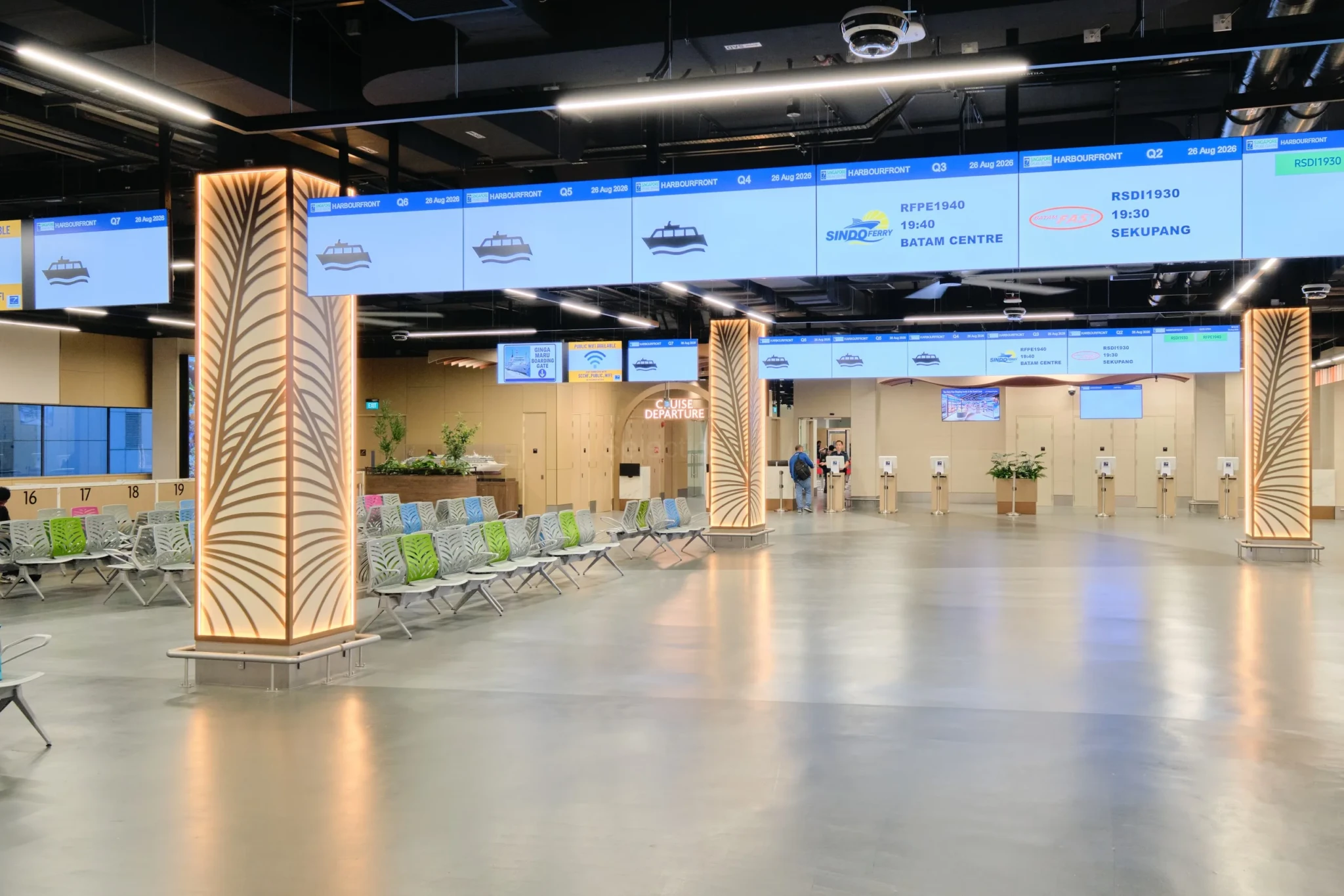 Digital departure boards and palm-patterned pillars in the ferry departure concourse