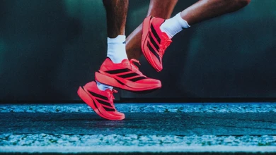 A runner mid-stride in the Adizero Adios Pro 5 on a blue athletic track