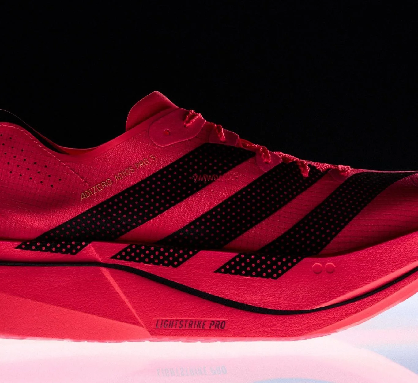The Adizero Adios Pro 5 race-day super shoe in red with black stripe detailing and perforated foam sections.