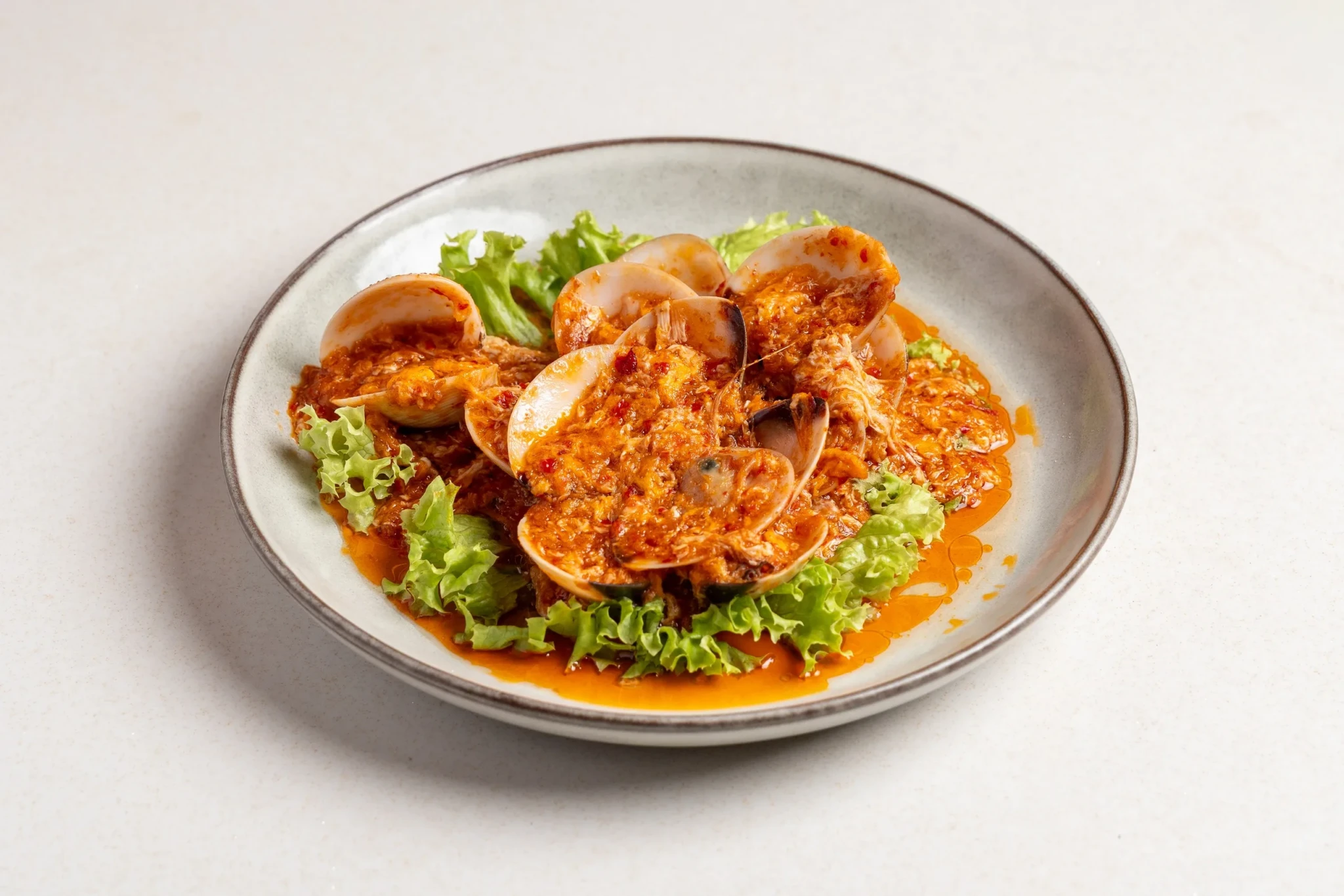 Chili crab dish with red sauce and roe on a ceramic plate