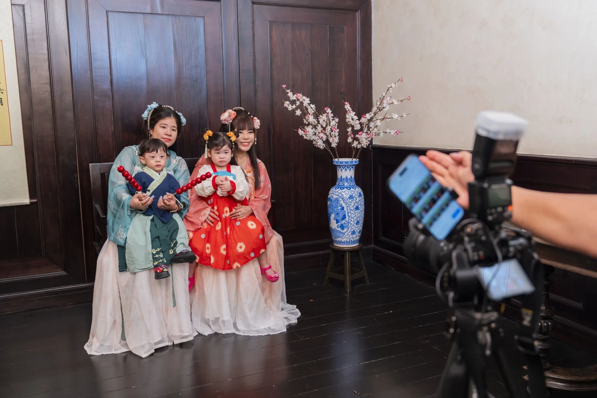 A family in traditional Chinese hanfu with floral headdresses posing for photographs