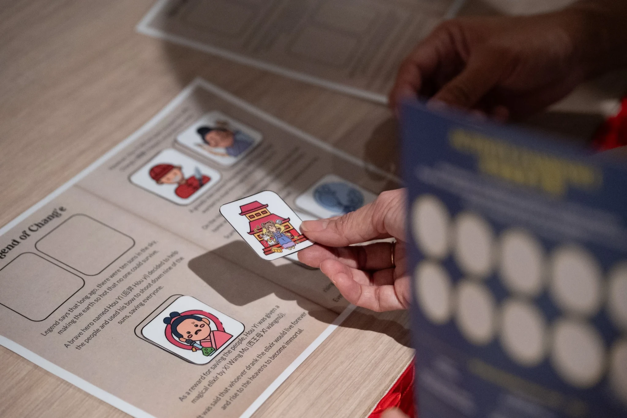 A visitor holding a sticker card featuring Chinese cultural imagery at the heritage game stations