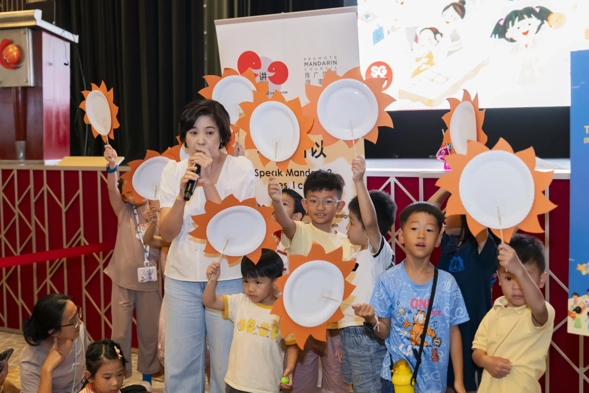 A storyteller engaging children with a sun-themed interactive activity during a Mid-Autumn storytelling session