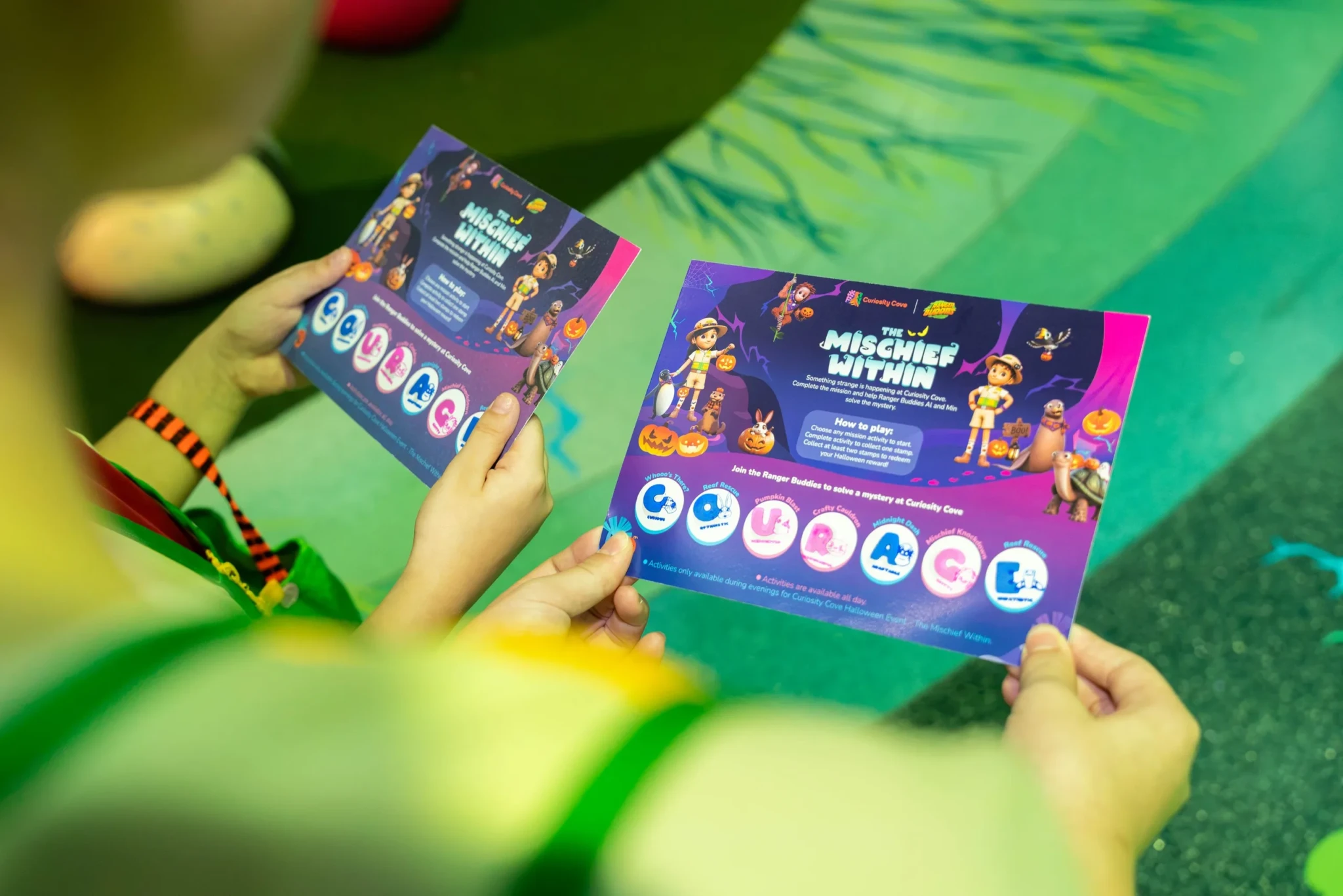 A child holding Quest Cards for The Mischief Within at Curiosity Cove