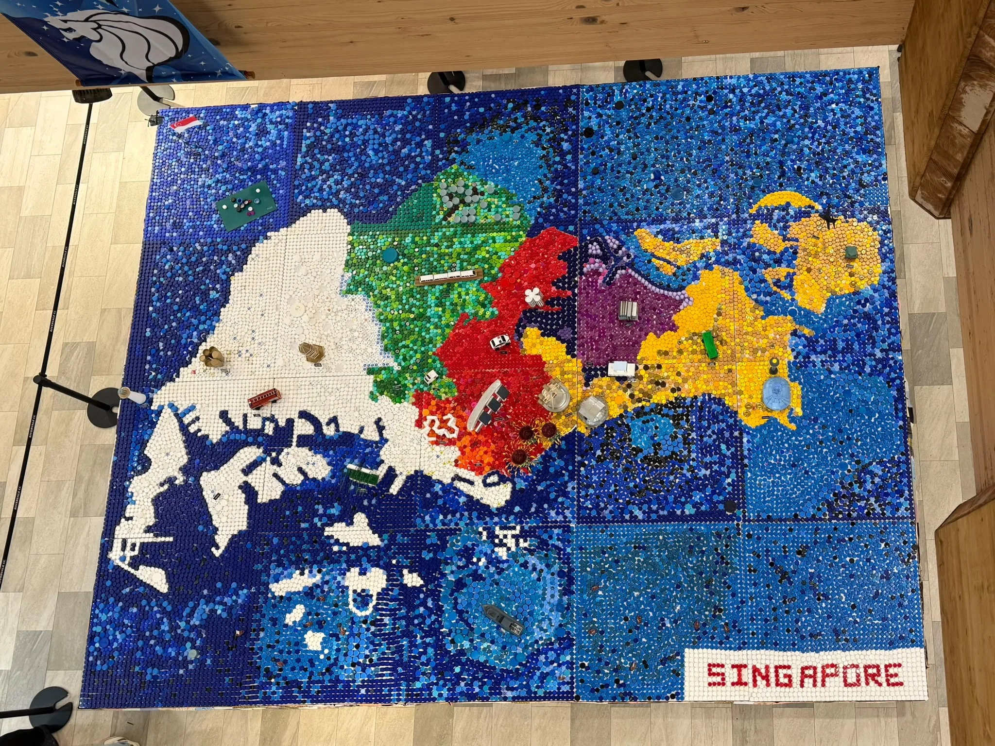 Map of Singapore made from coloured recycled bottle caps, with miniature landmarks and a SINGAPORE label