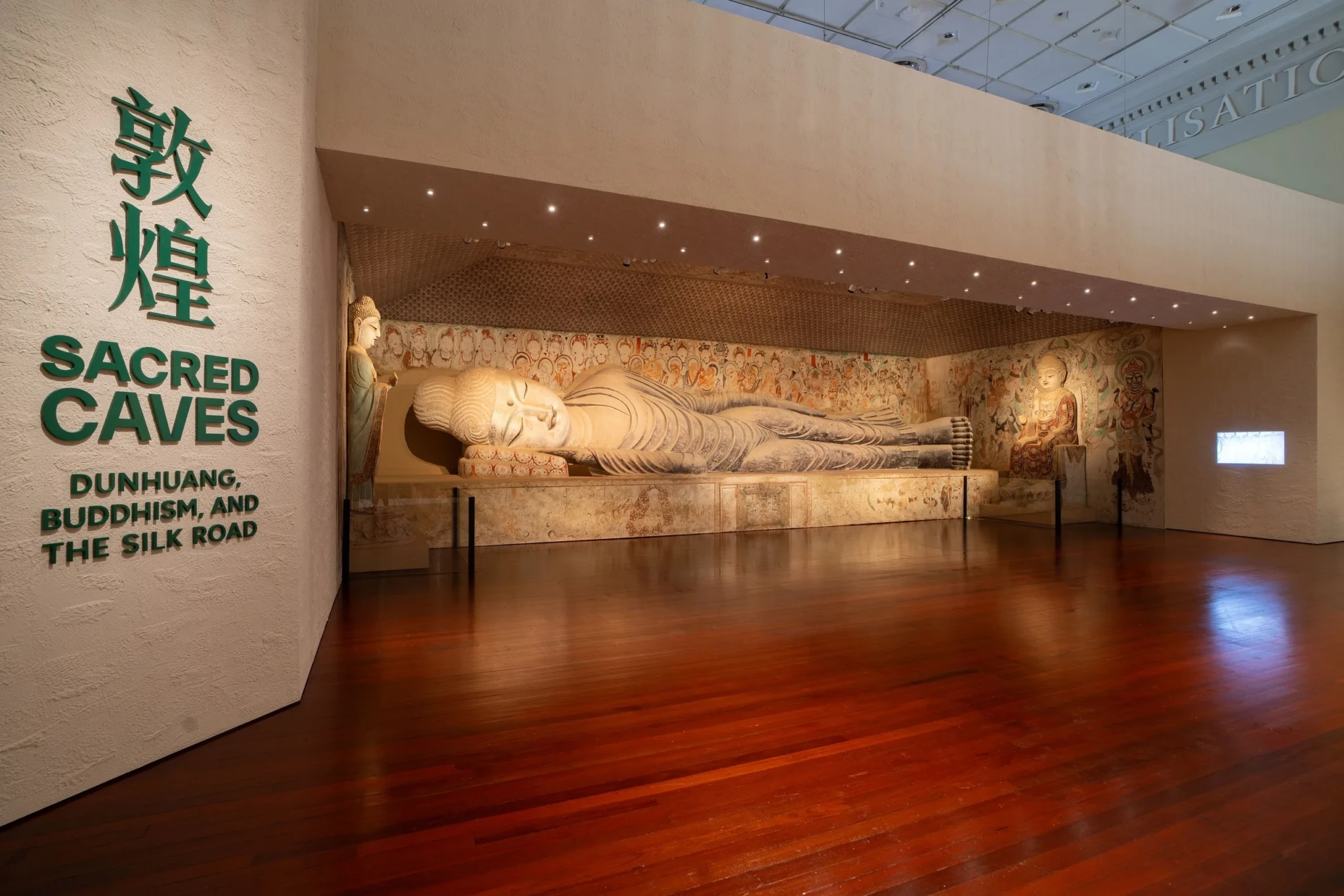 Life-size cave reproduction with reclining Buddha sculpture and painted Buddhist figures on walls