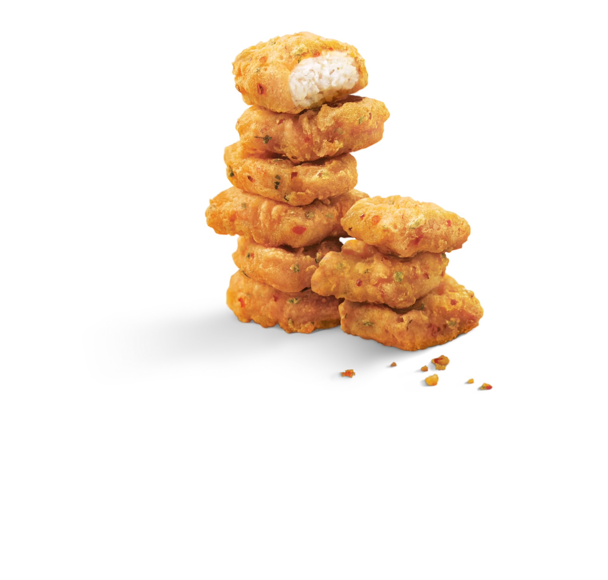 Golden fried Spicy Chicken McNuggets stacked in a pyramid with one cut in half showing white chicken interior