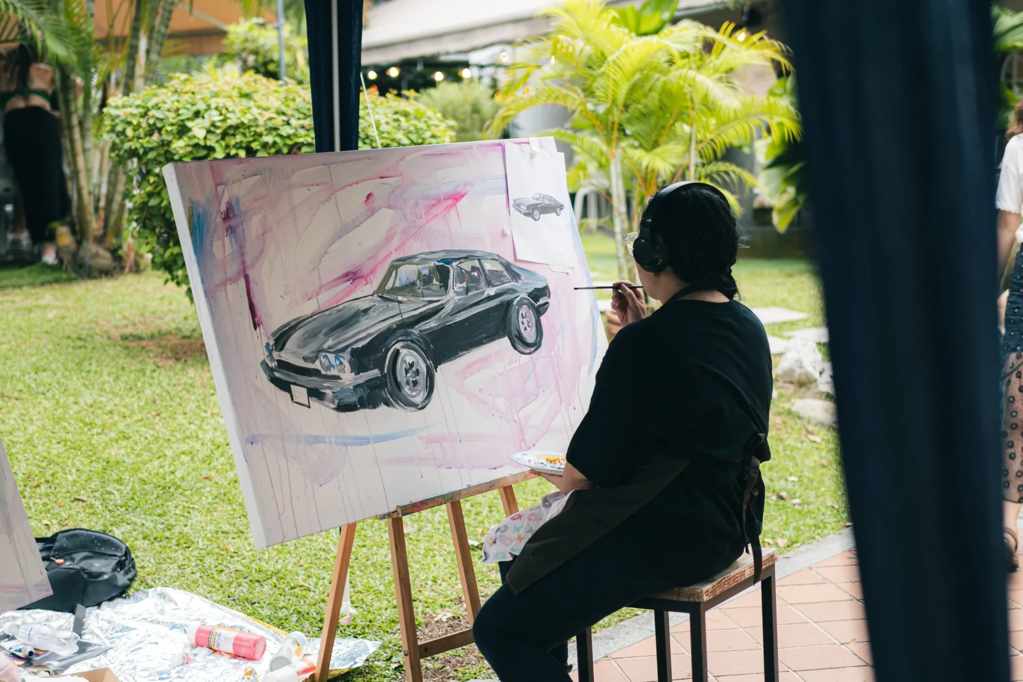 An artist painting a vintage car onto canvas