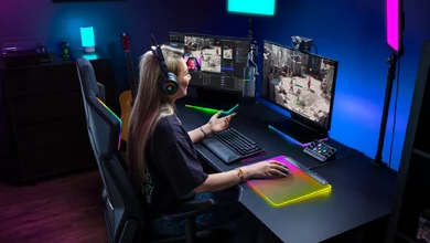 A streamer at an RGB-lit gaming desk with the Razer Kiyo V2 Pro on a stand beside the monitors