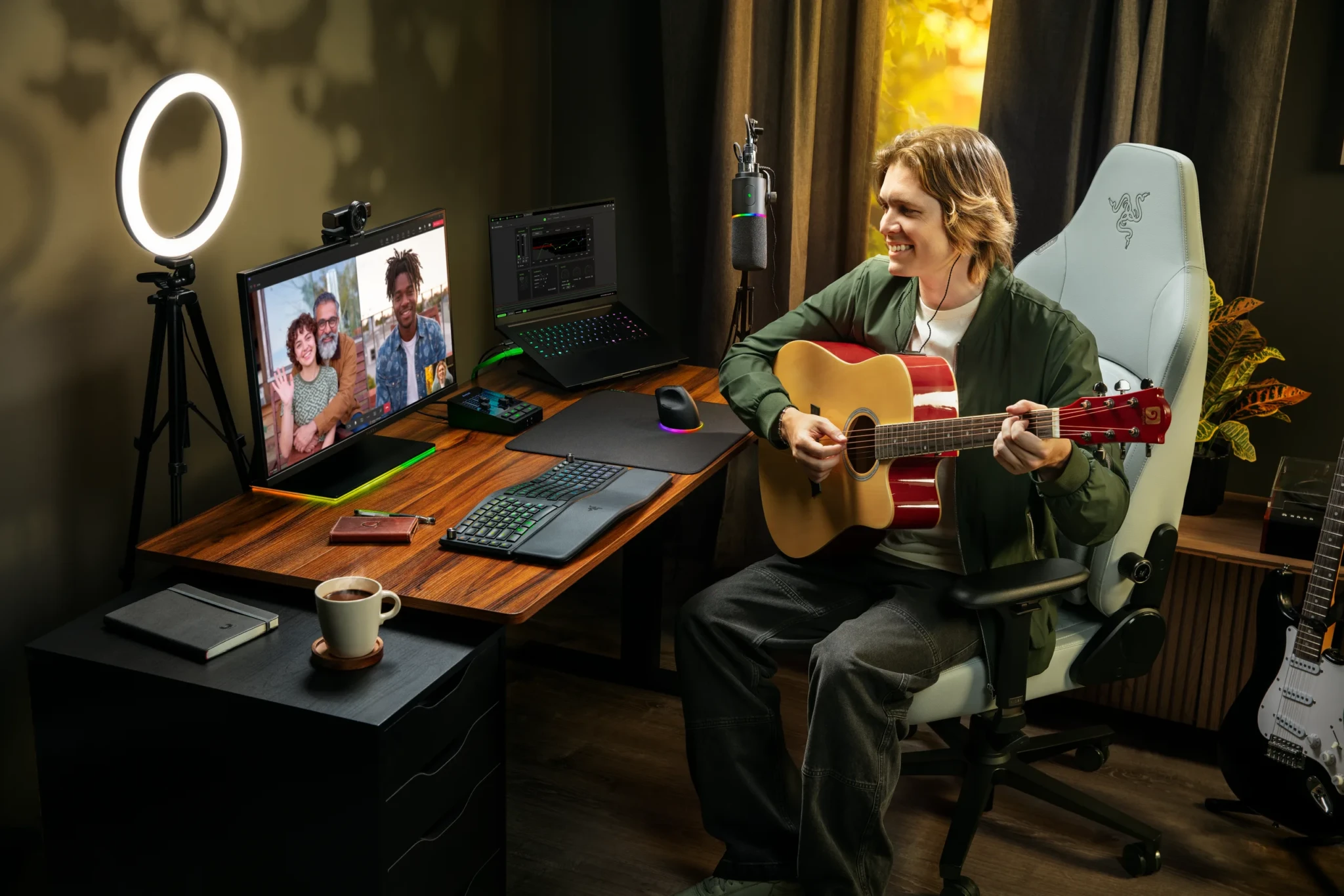 A musician plays an acoustic guitar in a streaming workspace with the Razer Kiyo V2 Pro and a ring light