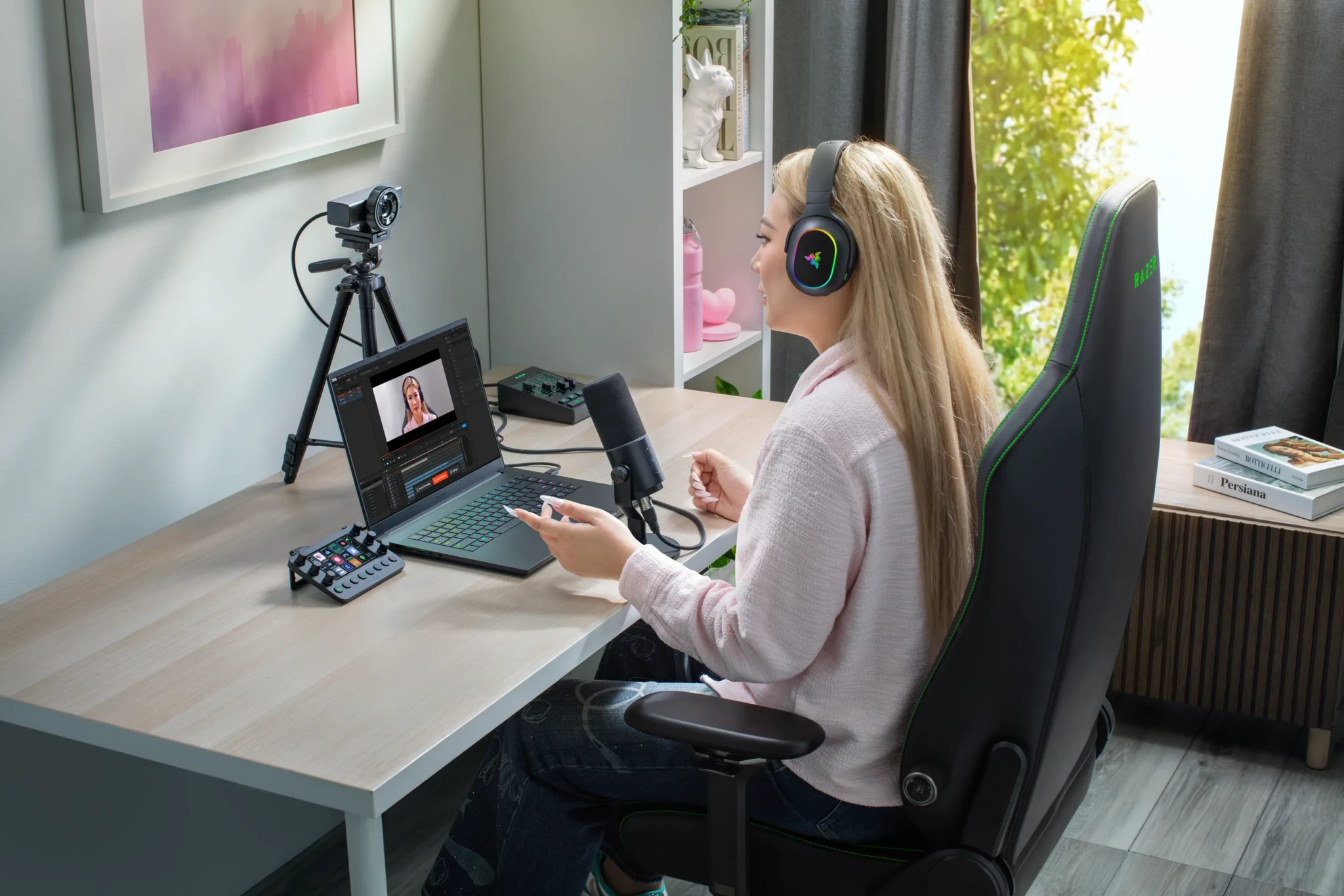 A content creator records a podcast with the Razer Kiyo V2 Pro mounted on a tripod and a remote guest on the monitor
