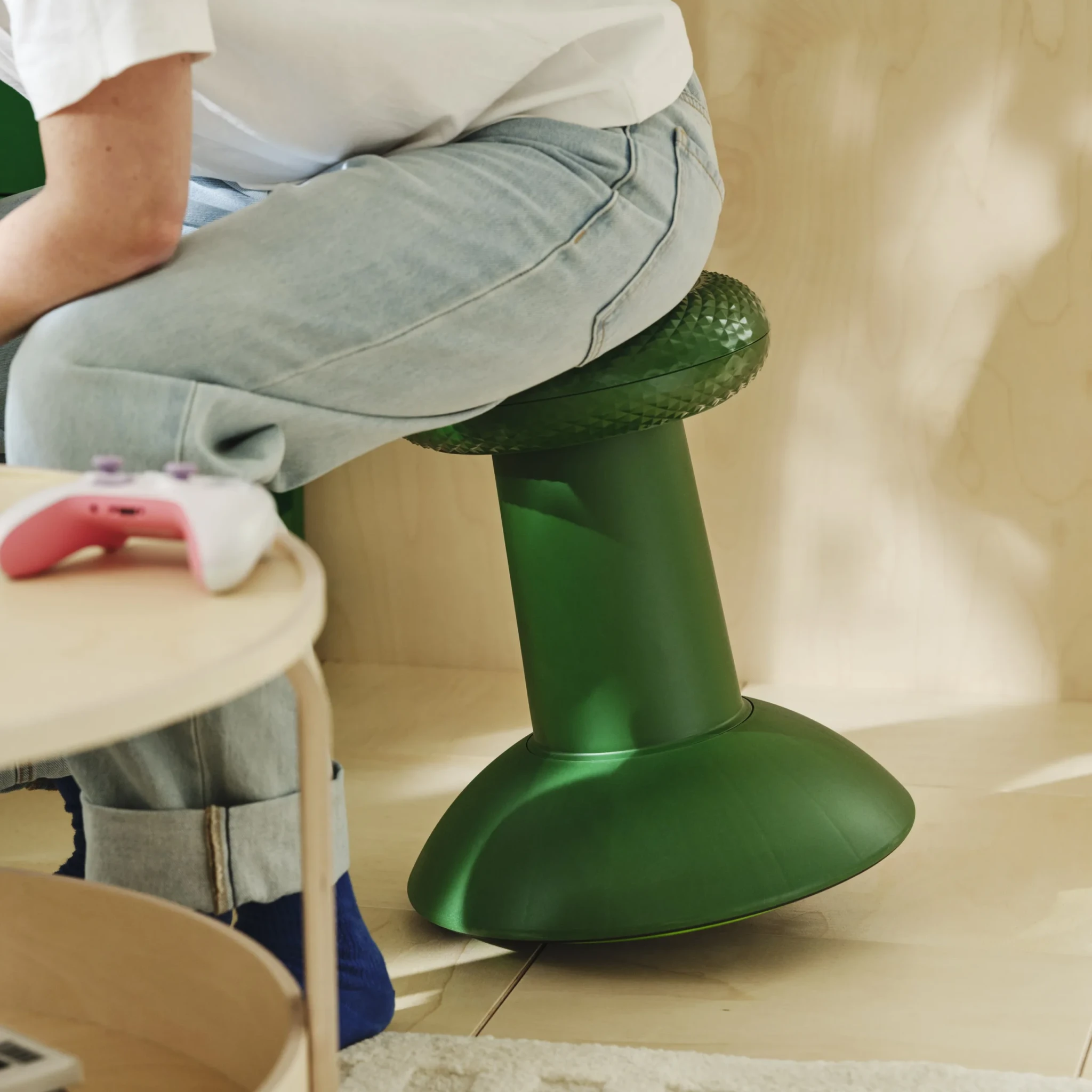 Person seated on the green YXSTABY Gaming thumbstick stool