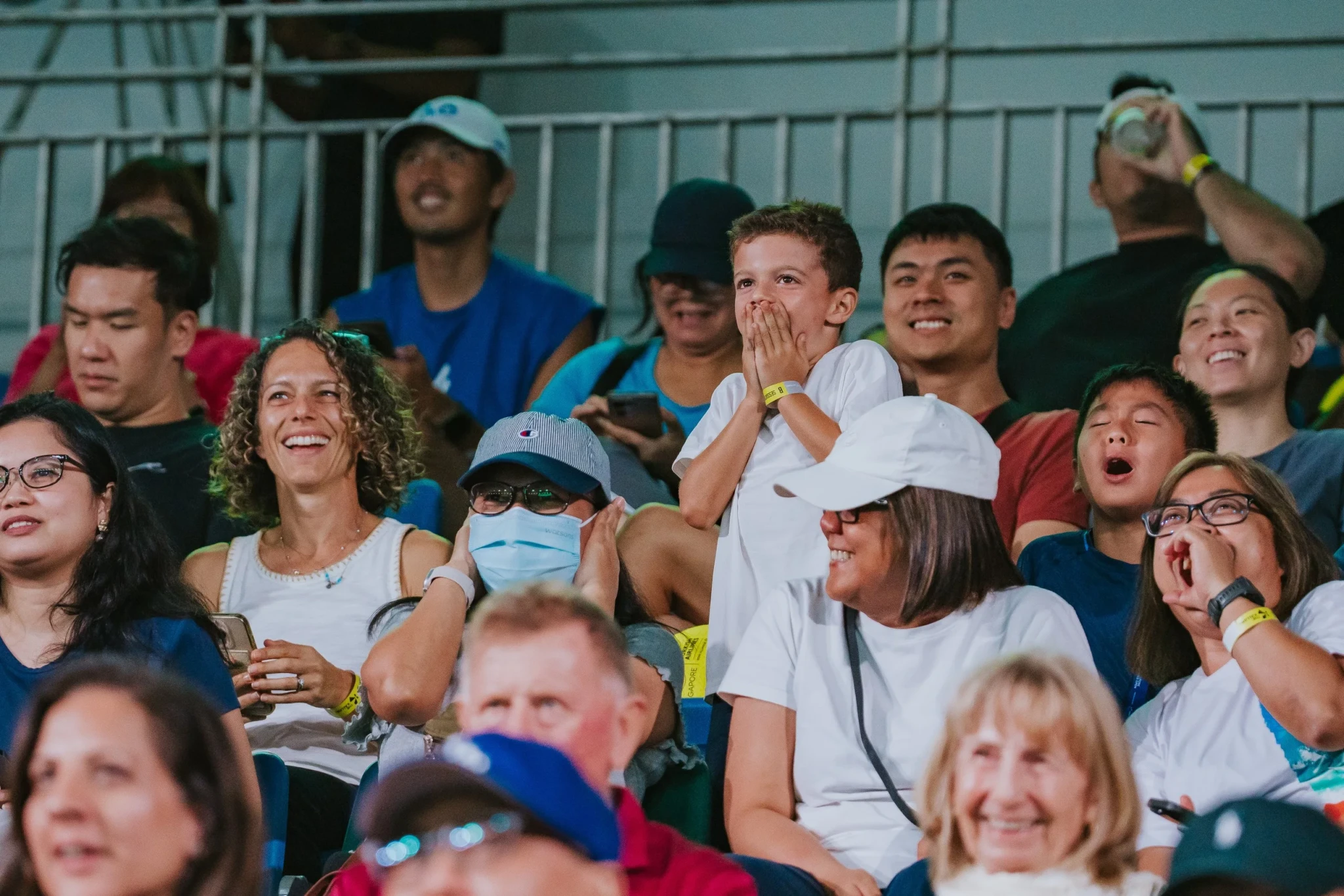 Crowds of smiling spectators in the stands at the Singapore Tennis Open