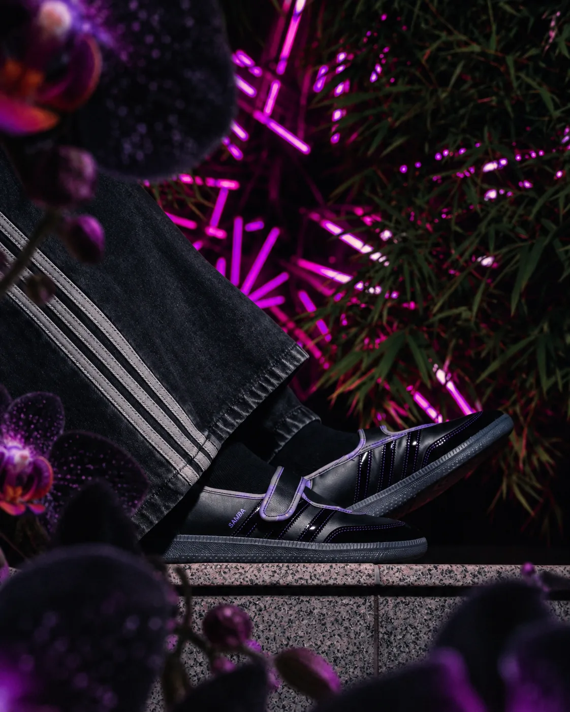 The Black Orchid Samba sneaker styled with flowers under purple neon lighting