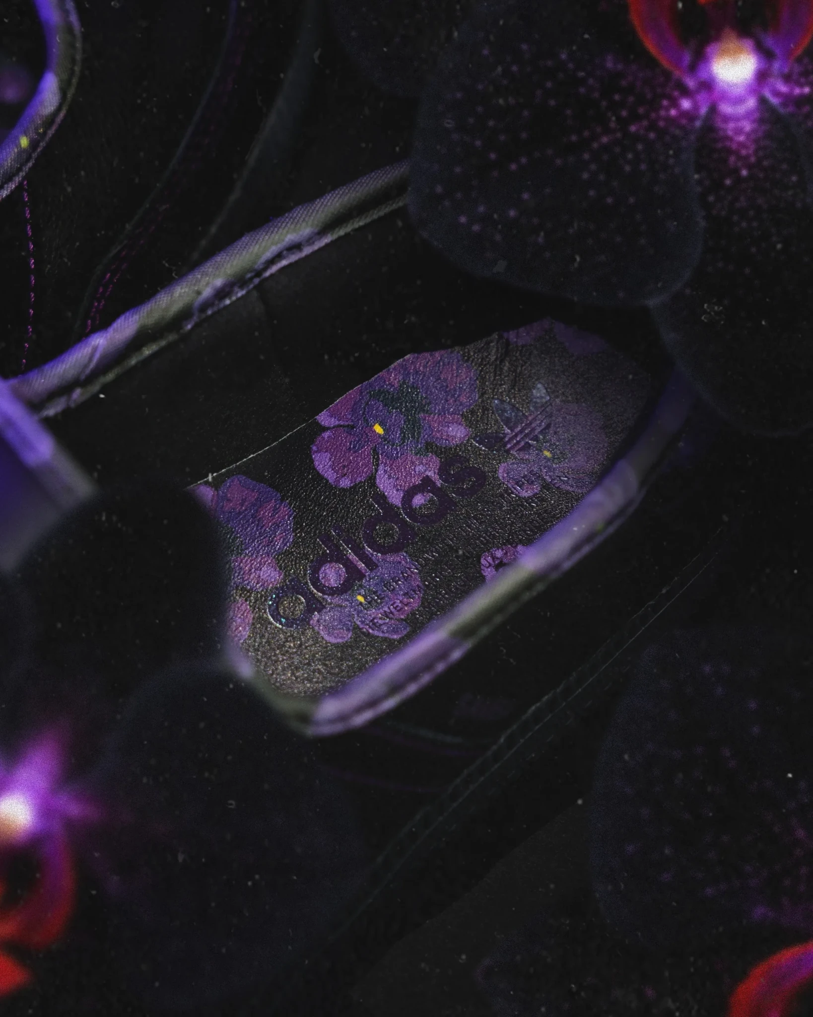Close-up of the floral detailing on the Black Orchid sneaker in purple and violet on black
