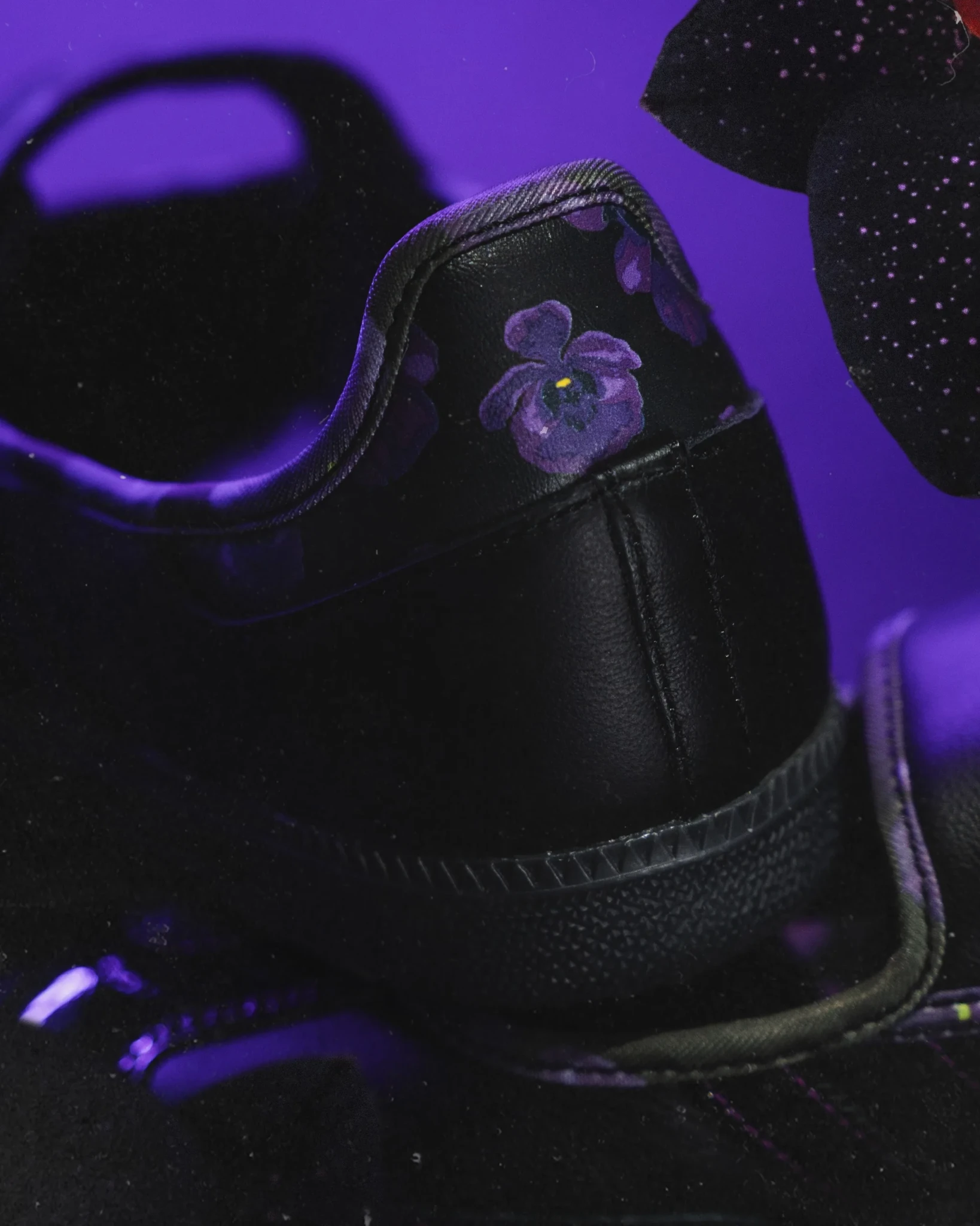 The heel of the Black Orchid Samba Jane with purple floral detail and violet accents