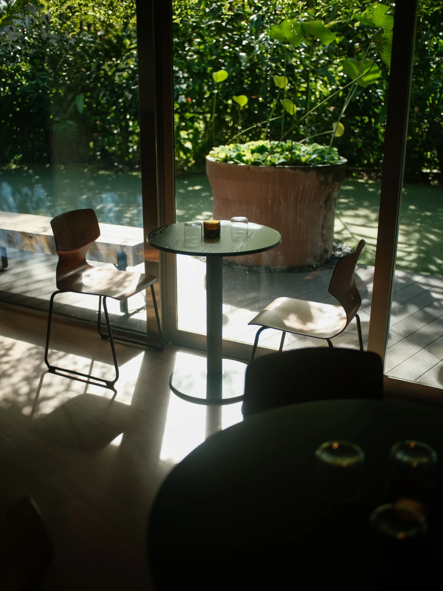 Third Floor's seating area with a round black table and modern chairs overlooking a planted garden courtyard