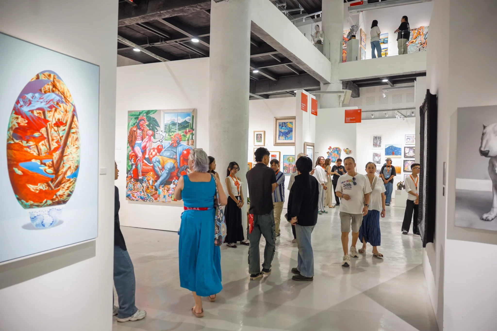 Visitors in a modern gallery space examining colorful contemporary artworks on white walls