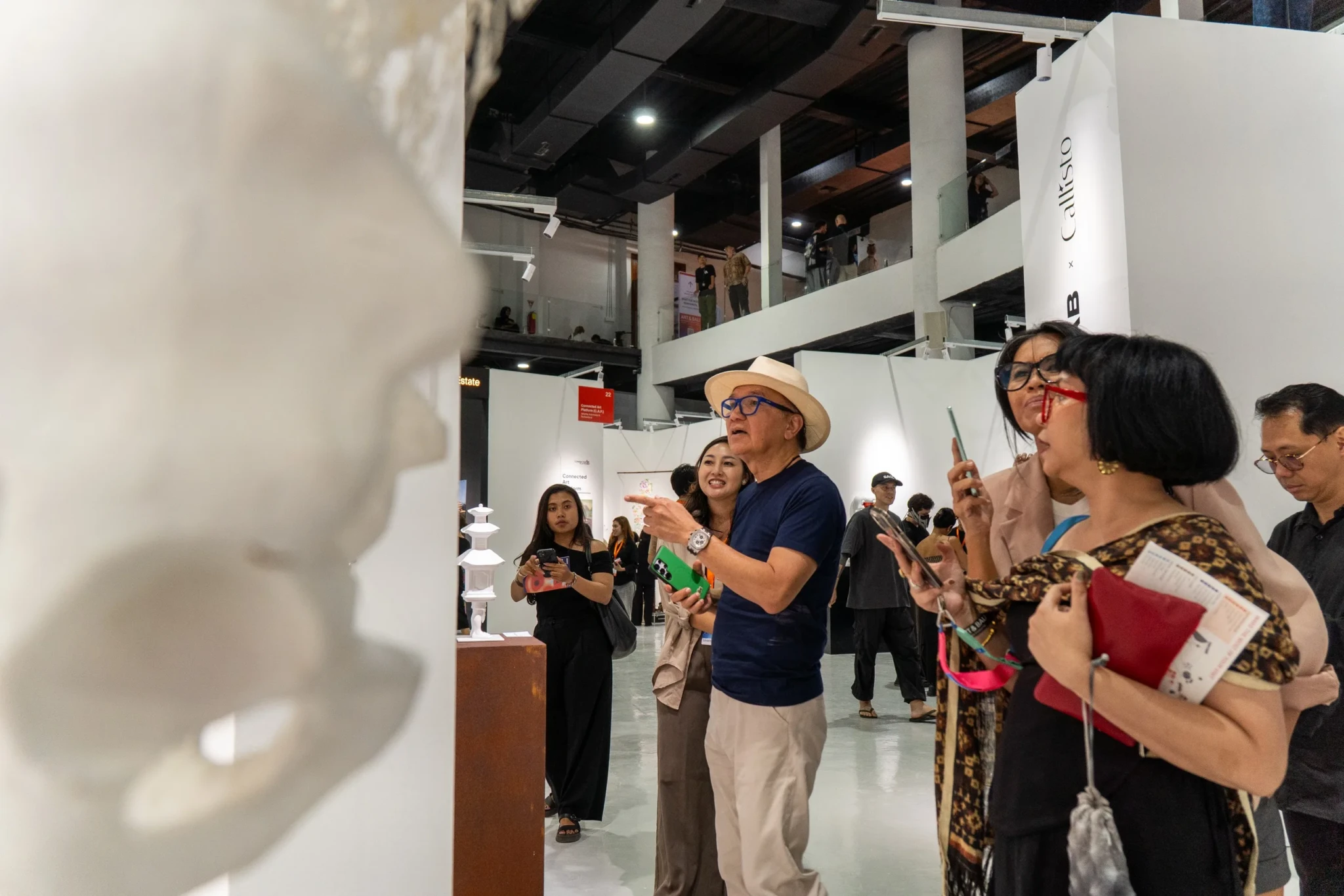 Visitors examining white sculptures at Art & Bali 2026, with one piece in sharp focus