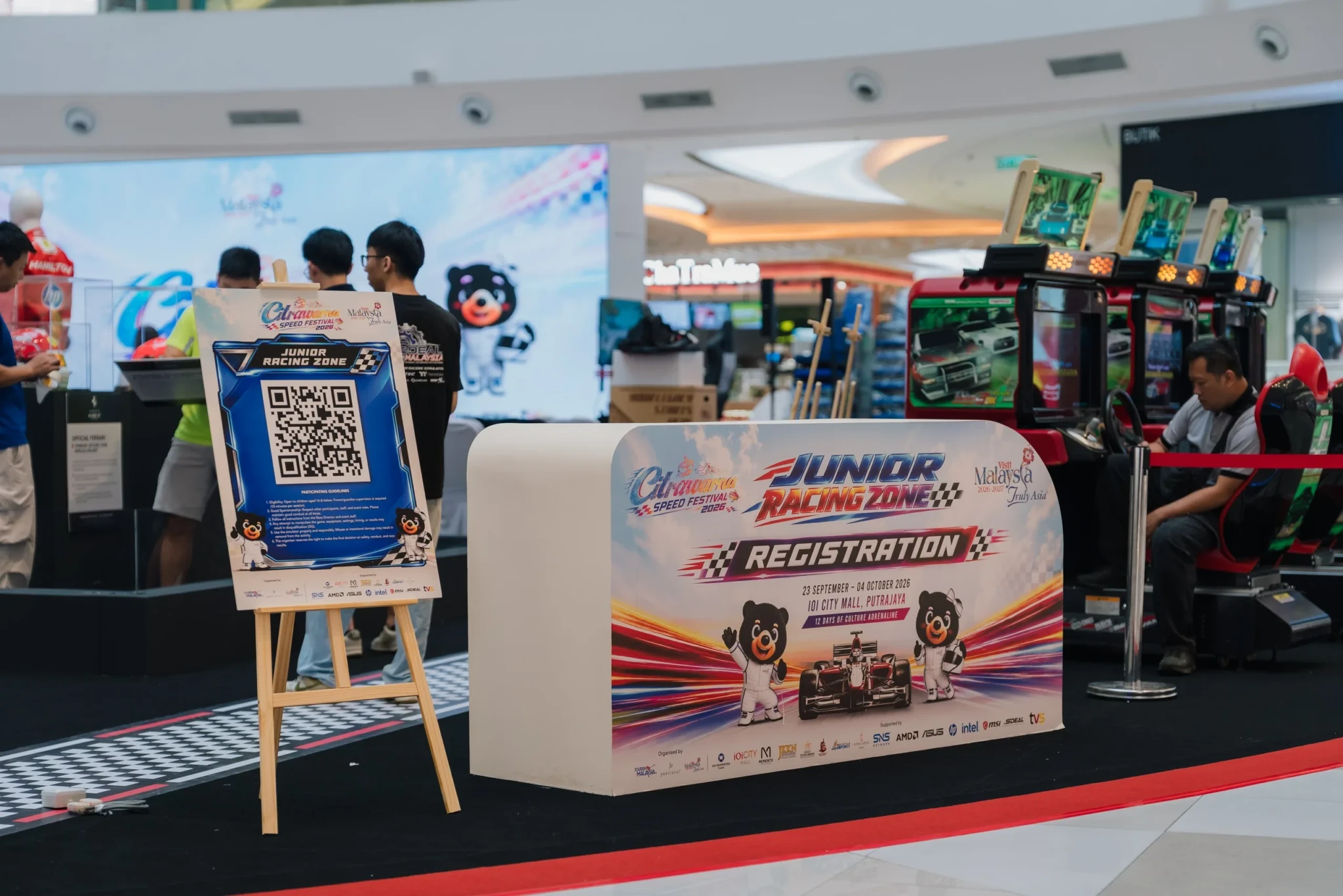 A Citrawarna Speed Festival 2026 poster and QR-code stand beside racing simulators