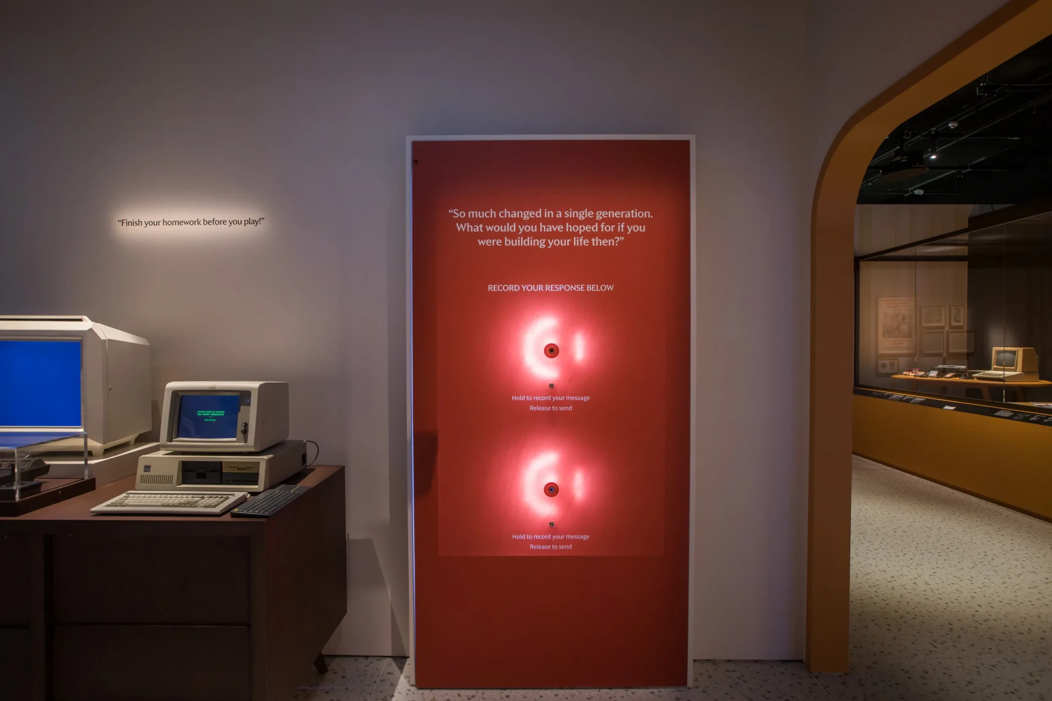 Interactive recording station with red panel and glowing buttons in museum gallery