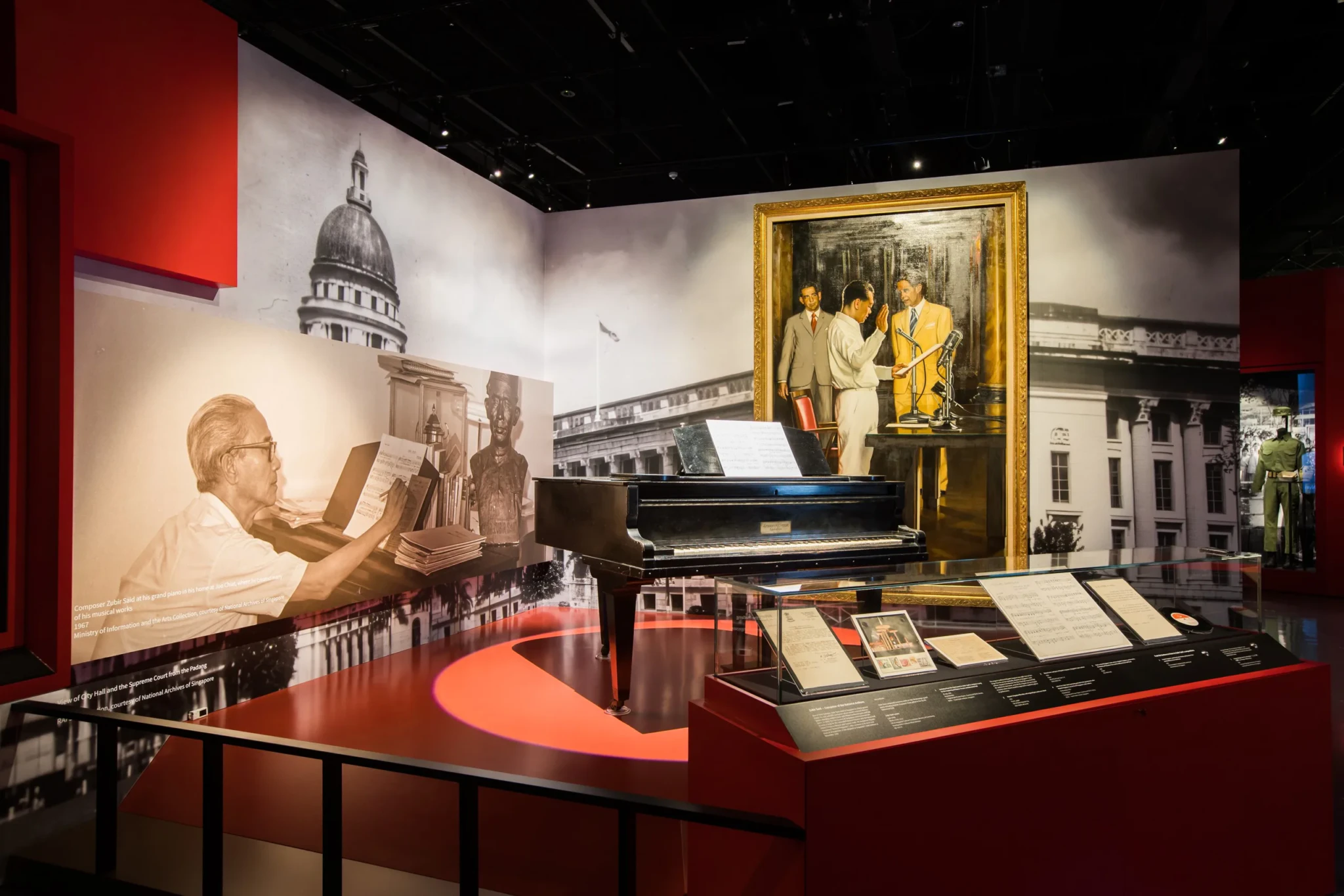 Zubir Said's piano surrounded by historical photographs and a gold-framed portrait in the Singapore History Gallery