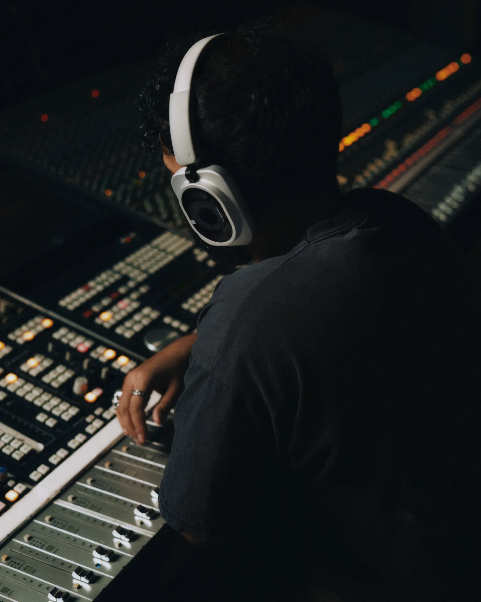 A person wearing Nothing Headphone (1) Pro at an illuminated mixing console