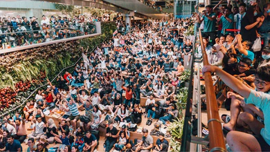Crowded multi-level atrium with hundreds of spectators during Changi Airport race season event