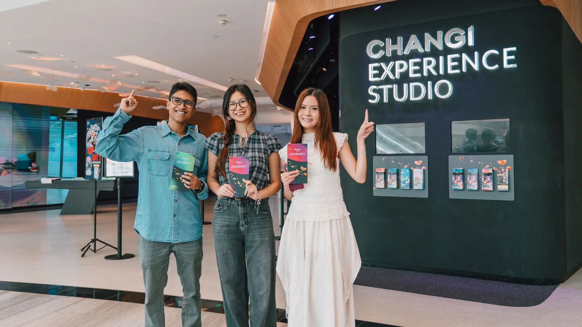 Four people posing in front of Changi Experience Studio sign at airport terminal
