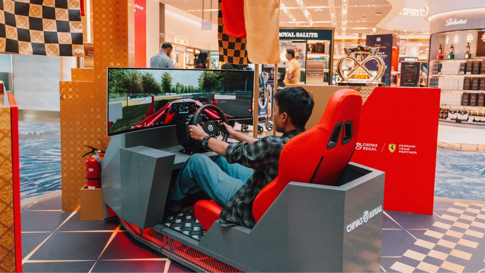 A visitor drives the Chivas Regal racing simulator with a race track on screen
