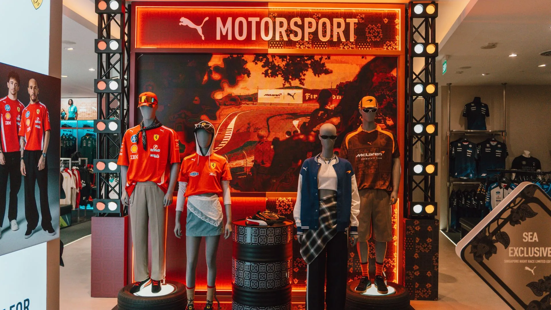 Motorsport merchandise display with racing team apparel on mannequins under glowing neon signage