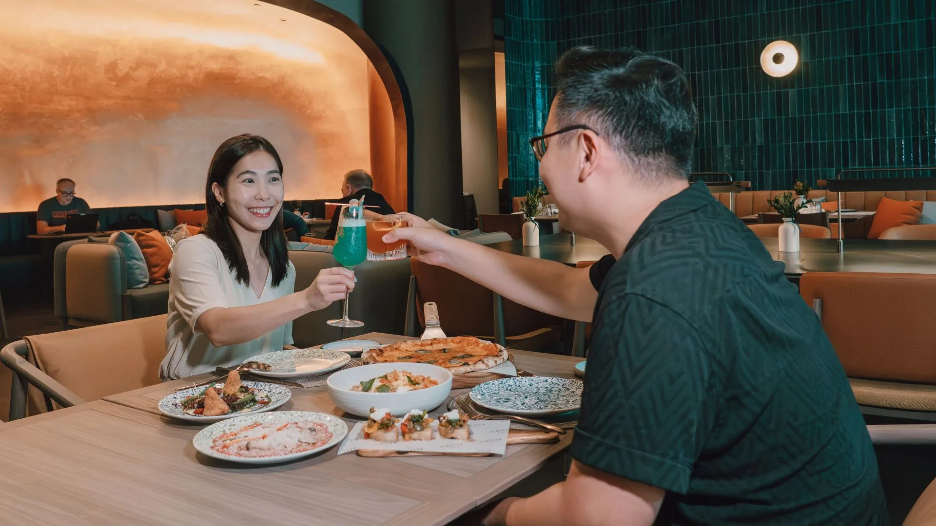 Two diners toast over pasta and seafood at Allora Ristorante