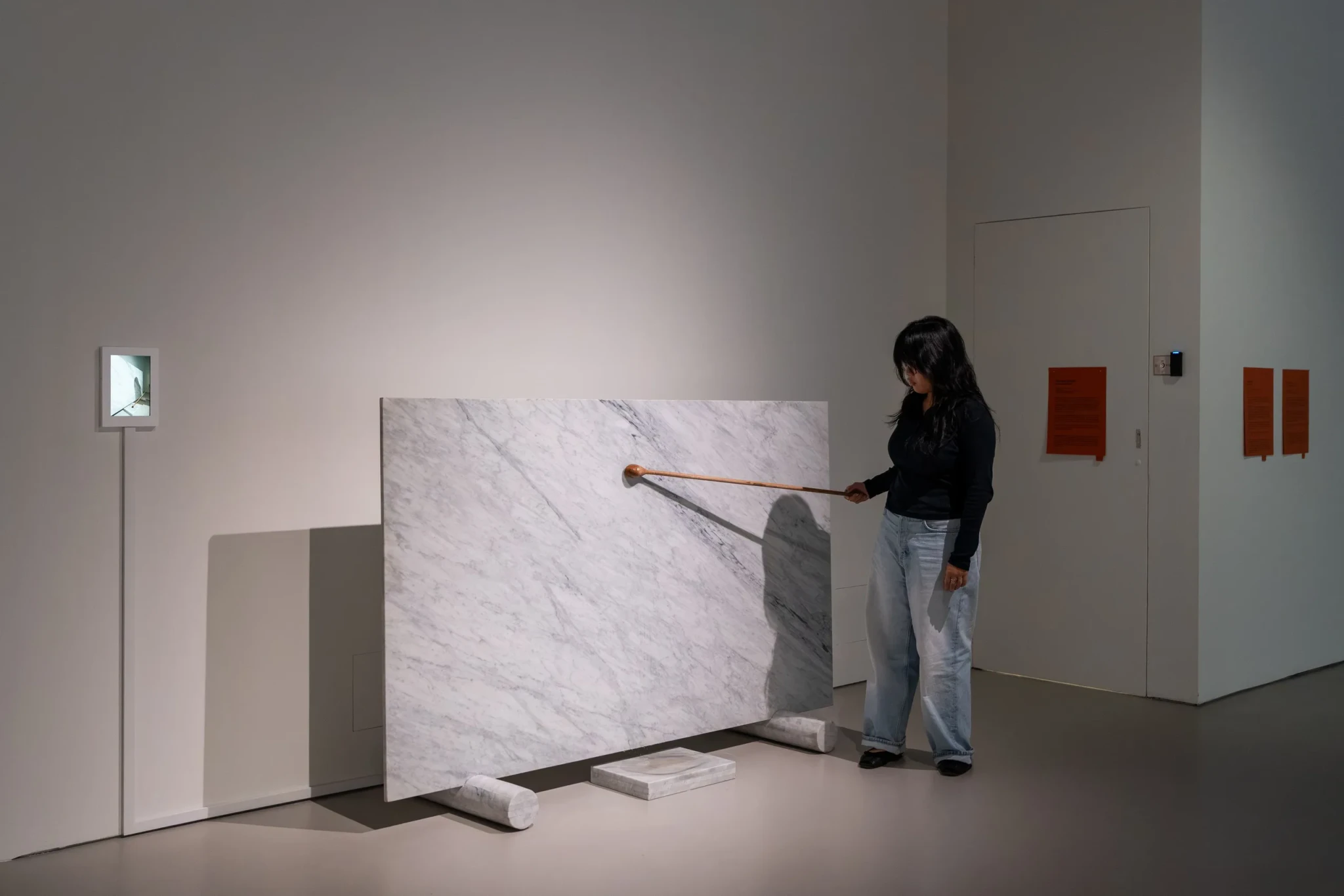 A visitor uses a wooden ladle over a marble panel in Gary-Ross Pastrana's Water Cuts (stone)