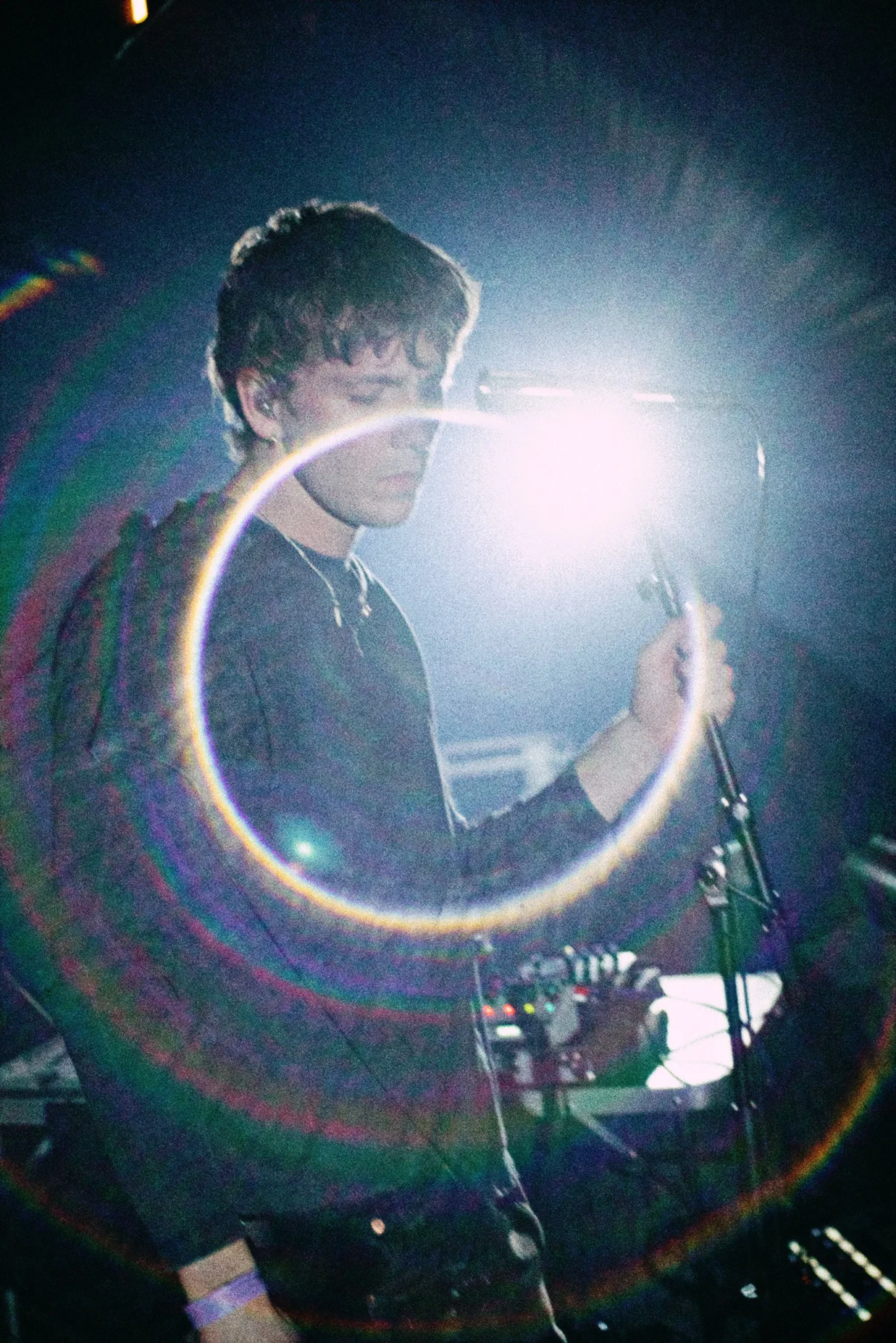 Oliver Symons performing on stage under bright, colourful lights