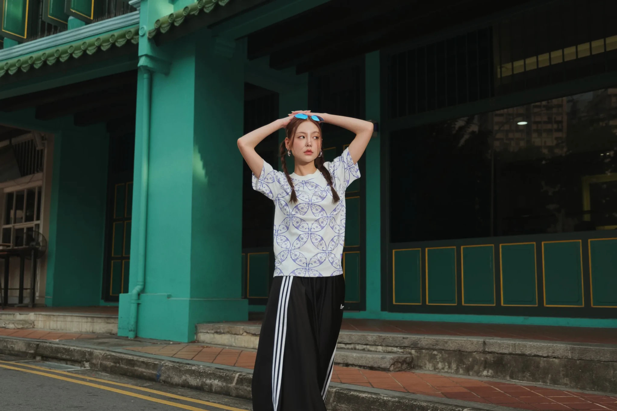 Model in an adidas x Audi Revolut F1 Team graphic t-shirt and black track pants with white stripes in front of Funan