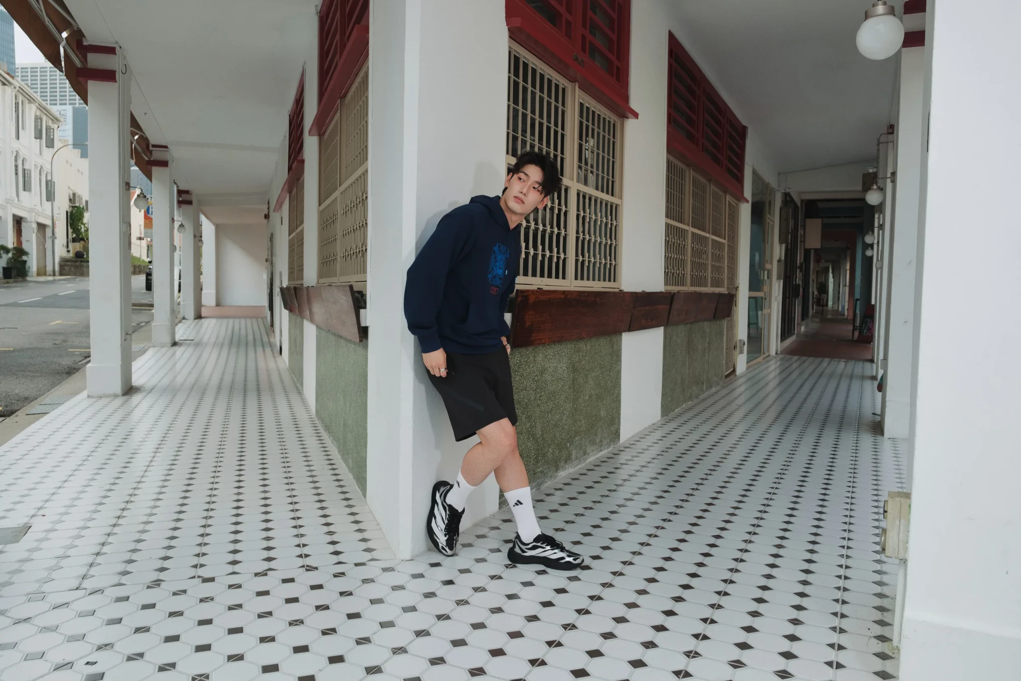 Male model in an adidas x Audi Revolut F1 Team navy hoodie and black shorts in a colonnade at Funan